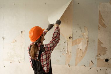 Duvardaki eski duvar kağıtlarını söken işçi ya da tamirci. Ev yenileme konsepti. Boşluğu kopyala
