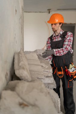 İnşaat enkazı toplayan kasklı genç bir inşaatçı. Ev tadilatı ve onarım. Boşluğu kopyala