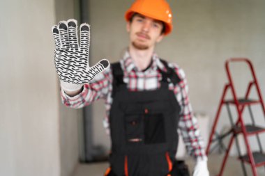 Erkek işçi, inşaatçı ya da tamirci inşaat alanında dur işareti ile reddetme jestini göstermeye hazır. Boşluğu kopyala