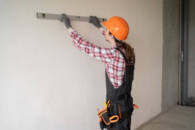 Müteahhit, tamirci, üniformalı müteahhit balon ruh seviyesini kullanarak duvarı ölçüyor. konut yenileme ve inşaat konsepti.