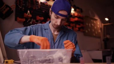 İş kıyafetlerindeki tamirci atölyede ya da garajda çalışan bir organizatör kutusundan vida seçiyor. Boşluğu kopyala