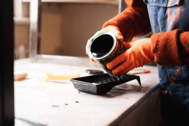 İşçi yakın plan plastik tepsiye siyah boya döküyor. Boşluğu kopyala