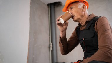 Mimar çalışma alanında kahve içiyor. İnşaat mühendisi yaşlı adam kahve molası veriyor. İnşaat işçisi dinleniyor. Emekli inşaat işçisi. Pankart