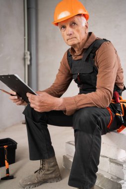 Tadilat sırasında inşaat alanında güvenlik kaskı takmış dalgın bir inşaatçının ya da tamircinin portresi. meslek, inşaat ve onarım kavramı.