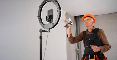 Güvenlik miğferi takmış inşaatçı ya da tamirci yenileme işlemi sırasında inşaat alanında video blogu kaydediyor. Daire tamiri ve yenileme konsepti. Boşluğu kopyala