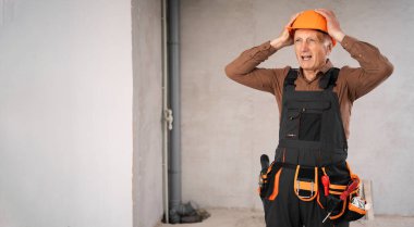 Tadilat sırasında inşaat alanında stres altında olan yorgun, üzgün inşaatçı ya da güvenlik kaskı takan yaşlı bir adam. meslek, inşaat ve onarım kavramı.