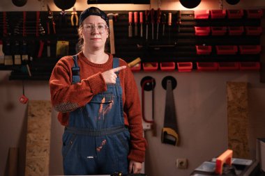 Tamir atölyesinde çalışırken ücretsiz uzay reklamını gösteren tulumlu ve gözlüklü bir kadın tamirci. Boşluğu kopyala