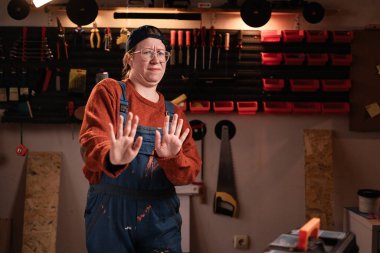 Tulumlu ve gözlüklü kadın tamirci hayır diyor. Tamir atölyesinde çalışırken reddedilen kadınlar öneriyor. Boşluğu kopyala