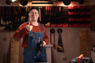 İş tulumlu kadın tamirci ve onaylı gözlüklü. Tamir atölyesinde çalışırken motivasyon ya da teşekkür. Boşluğu kopyala