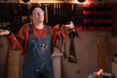 Tulumlu ve gözlüklü üzgün kadın tamirci tamirhanede çalışırken bilmediklerini söylüyor. Boşluğu kopyala