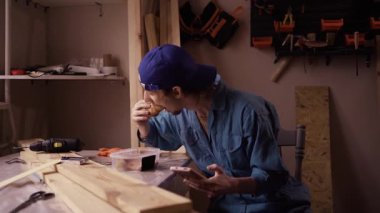 Garajında oturan, yemek yiyen ve sosyal medyayı karıştıran üniformalı bir erkek tamirci. Küçük bir atölyede gezici bir cihazla öğle yemeği molası veren işçiler.