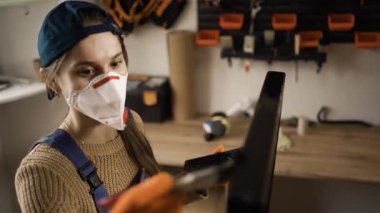 Mobilya detaylarını boyayan koruyucu maske takan bir kadın. Boyacı boya ve boya fırçasıyla mobilya tadilatı yapıyor. Boşluğu kopyala