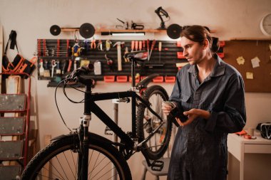 Bisiklet tamiri ve bakım atölyesinde. Bisiklet tamircisi bisiklet tamirinde çalışırken bir dolar nakitle cüzdanı açık tutuyor. insanlar, iş, finans ve para kavramı