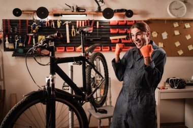 Bisiklet tamiri ve bakım atölyesinde. Bisiklet tamircisi, bisiklet tamirinde çalışırken yaptığı jesti kutluyor. Boşluğu kopyala