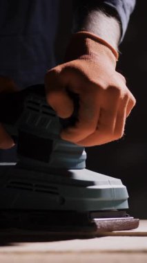 Tahta işleme konsepti. Marangoz ellerinin Macro görüntüsü zımpara makinesiyle ahşap mobilya detaylarını kumluyor. Boşluğu kopyala