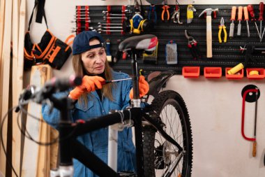 Bisiklet dükkanında teknik uzmanlık. Orta yaşlı bayan bisiklet tamircisi atölyede bir bisikleti tamir ediyor. Boşluğu kopyala