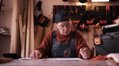 Sinirli kadın marangoz atölyesinde mali belgeler ve faturalar üzerinde çalışıyor. Küçük işletme iflası, mali kriz, borç ve profesyonel başarısızlık kavramı.