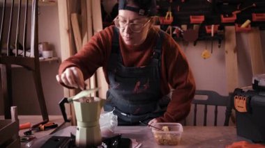 Profesyonel kadın esnaf yemek molası veriyor ve çalışma alanında demlenmiş kahve içiyor. İş yerinde öğle yemeği kavramı, bir zanaat girişimcisinin yaşam tarzı ve bir marangoz dükkanına zorla girme..