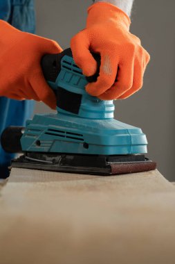 Sander makinesini tahta üzerinde kullanarak insan ellerine yakın çekim. İnşaat konsepti Marangozluk atölyesi