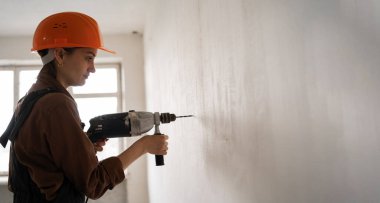 Çekiç matkabı kullanan kadın inşaat işçisi. Havalı çekiç matkaplı kadın duvarda delik açıyor. Pankart. Boşluğu kopyala