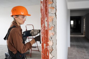 Çekiç matkabı kullanan kadın inşaat işçisi. Havalı çekiç matkaplı kadın duvarda delik açıyor. Boşluğu kopyala