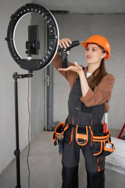 Kadın blogcu inşaat alanında halka ışığıyla video kaydediyor. Onarım, inşaat ve inşaat konsepti. Boşluğu kopyala