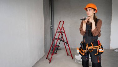 Kadın Mimar. Kadın mimar ya da inşaat işçisi cep telefonundan ses asistanıyla konuşuyor. Teknoloji, onarım, inşaat ve inşa konsepti. Boşluğu kopyala