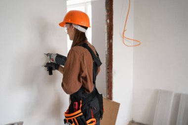 Çekiç matkabı kullanan kadın inşaat işçisi. Havalı çekiç matkaplı kadın duvarda delik açıyor. Boşluğu kopyala