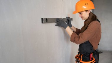 Ev yenileme çalışmaları sırasında ruh seviyesini kullanarak beton duvar ölçen kadın inşaat işçisi ya da inşaat işçisi. Pankart. Boşluğu kopyala