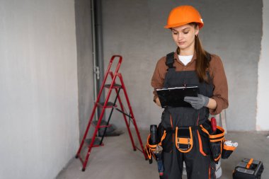 Yeni binada panosu olan inşaat işçisi ya da inşaatçının portresi. meslek, inşaat ve onarım konsepti. Boşluğu kopyala