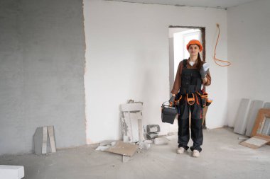 Alet çantası yürüyüşü yapan kadın tamirci tamamlanmamış binaya giriyor. Yenileme dairesi aletleri. Ev konseptini onar