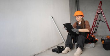 Kadın tamirci, ustabaşı ya da üniformalı ya da inşaatçı elinde pano ve tadilat planı tutan. Onarım, inşaat ve inşaat konsepti. Pankart. Boşluğu kopyala