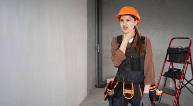 Kadın Mimar. İş tulumu içinde dalgın bir kadın mimar ve tamamlanmamış binada yeni bir fikir düşünüyor. Onarım, inşaat ve inşaat konsepti. Pankart. Boşluğu kopyala