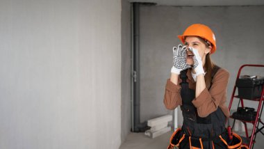 Kadın Mimar. Kadın mimar bitmemiş binada iyi haber diye bağırıyor. Onarım, inşaat ve inşaat konsepti. Pankart. Boşluğu kopyala