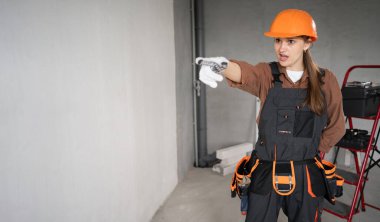 Kadın Mimar. Kızgın Kadın Mimar bitmemiş bir binada seni işaret ediyor. Onarım, inşaat ve inşaat konsepti. Pankart. Boşluğu kopyala