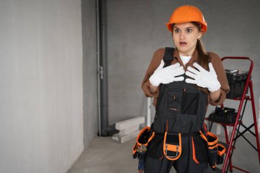 Kadın Mimar. Kadın mimar kendini işaret ediyor. Aman Tanrım, tamamlanmamış binada el kol hareketi yapıyorum. Onarım, inşaat ve inşaat kavramı.