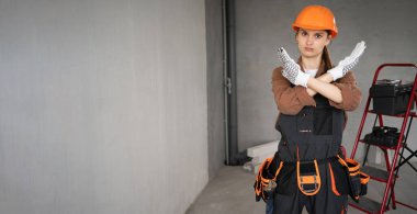 Kadın Mimar. Kadın mimar tamamlanmamış binada çapraz silah bloğu hareketi gösteriyor. Onarım, inşaat ve inşaat konsepti. Pankart. Boşluğu kopyala