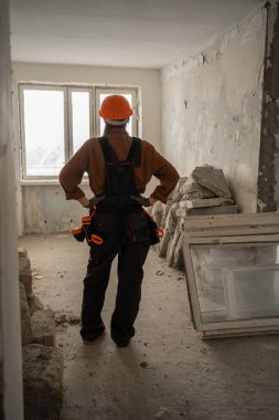 Ev tadilatından önce kask ve tulum giyen profesyonel kadın müteahhitlerin arka planda duruşu. Ev yenileme ve inşaat planlayan kadın işçiler.