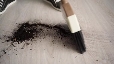 Plastik süpürge ve yeşil faraş kullanarak yere dökülen toprak ya da toprağı, ev temizliği, ev işi ve temizlik kavramını temizleyin..