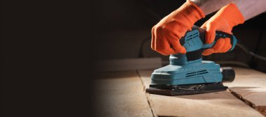 İnşaat konseptinde zımpara makinesiyle erkek elinin yakın çekimi.