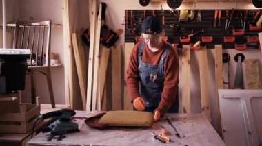 Profesyonel restorasyon atölyesinde eski döşemeleri eski koltuğundan söken profesyonel bir kadın restoratör..