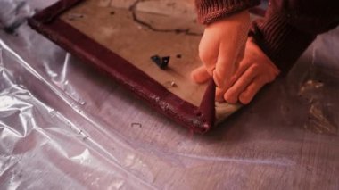 Profesyonel mobilya restoratörü, özel bir restorasyon atölyesinde yenilenmesi için eskimiş kumaşı eski bir ahşap sandalyeden ayırıyor..