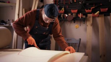 Restorasyon atölyesinde çalışan ve sandalye döşemesi için kesici bıçakla sünger kesen kadın restoratör.