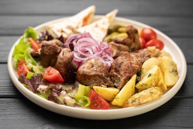 Restoranda servis edilen kızarmış patates ve taze sebzelerle ızgara şiş şiş kebap. Boşluğu kopyala