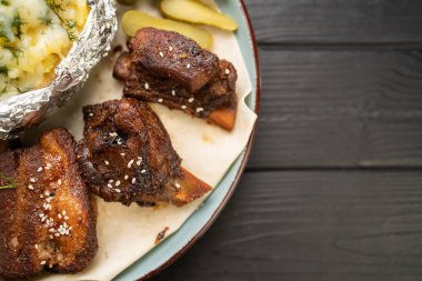 Tahta bir masanın üzerinde fırında patates dilimleri olan sulu, kavrulmuş et kaburgalarını kapatın. Biftek evi reklamı için profesyonel gurme yemek fotoğrafçılığı. Restoran menüsü kavramı.