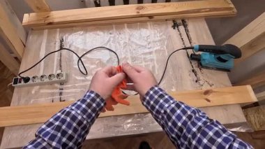 Turuncu eldiven giyen bir adam ahşap bir tahtayı zımparalamaya hazırlanıyor. Konsept: DIY, ev yenileme, hobi