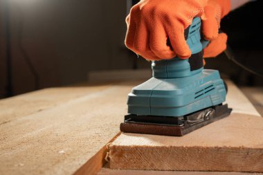 İnşaat konseptinde zımpara makinesiyle erkek elinin yakın çekimi.