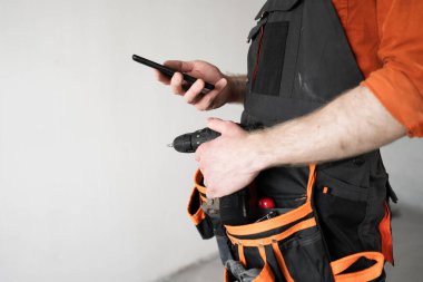 Akıllı telefondan mesaj gönderen ya da cep telefonu uygulaması kullanan bir mimar, yakın plan. Onarım, inşaat ve inşaat kavramı