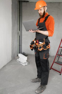 İnşaat alanında dizüstü bilgisayar kullanan müteahhit ya da müteahhit. Boşluğu kopyala