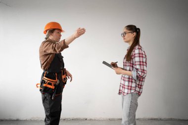 Mimar ya da müteahhitle birlikte pano kullanarak tadilat planlarını tartışan bir müşteri. Boşluğu kopyala
